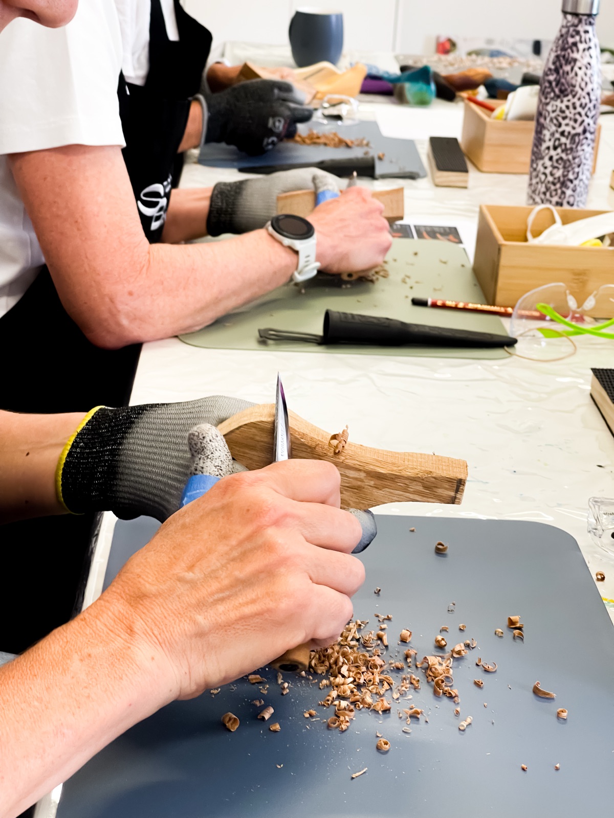 A recurring hands-on workshop in progress at the studio: participants in protective gloves working with carving tools and wood at the long workshop tables